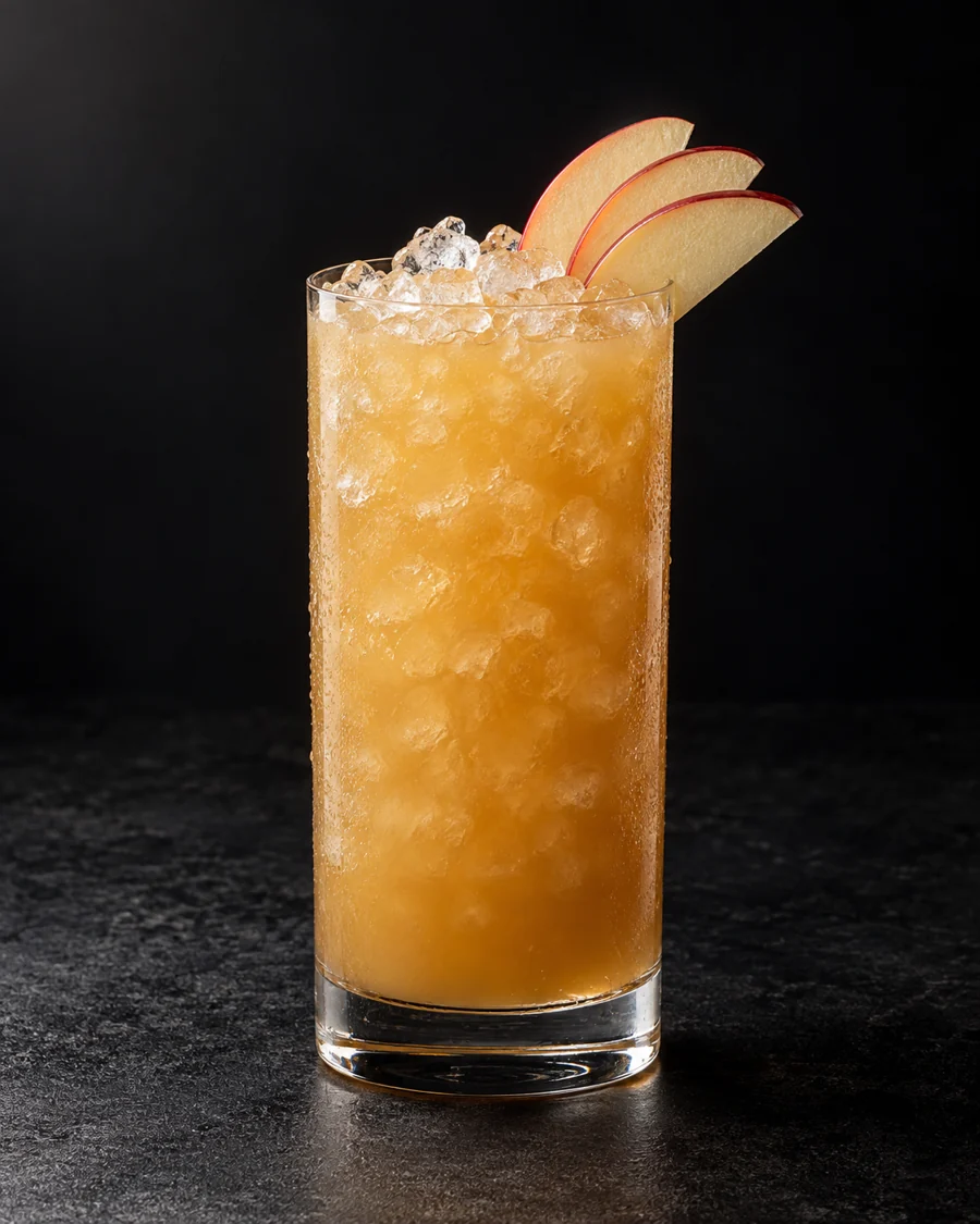Cloudy caramel-gold drink in a highball over pebble ice with a three-slice apple fan.
