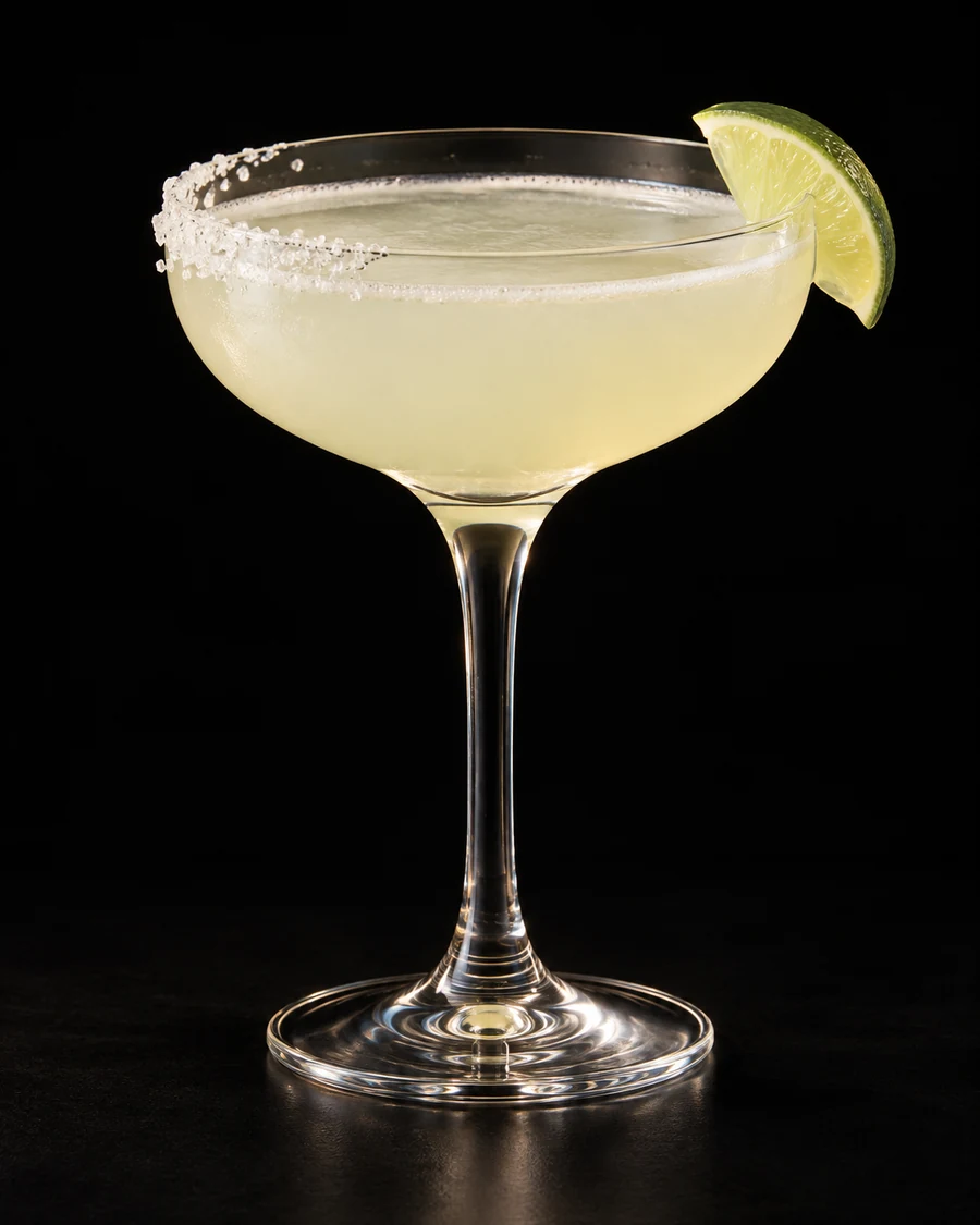 Non-Alc Classic Margarita in a coupe, serve without ice, with Lime wedge; optional half-salt rim, against a black background.